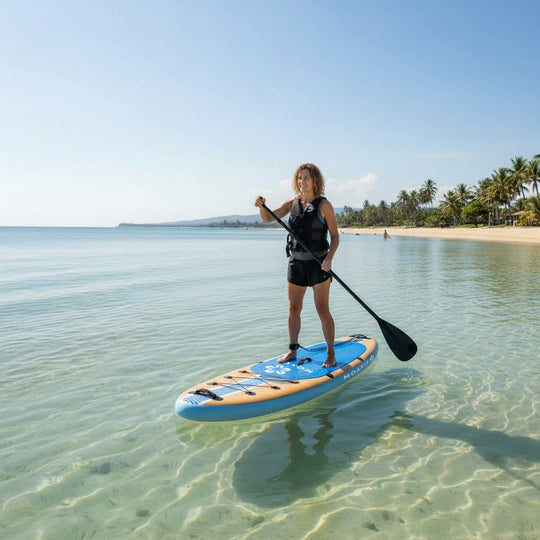 Person paddleboarding on a clear beach with palm trees in the background