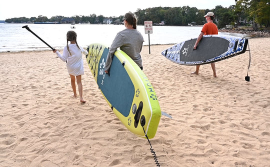 Paddlers with Trekker boards near the water's edge, ready for a launch.