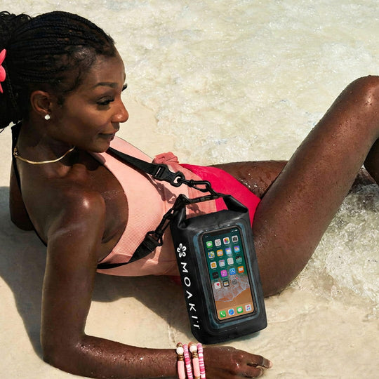 Woman lying on a beach with a Moakii waterproof phone case.