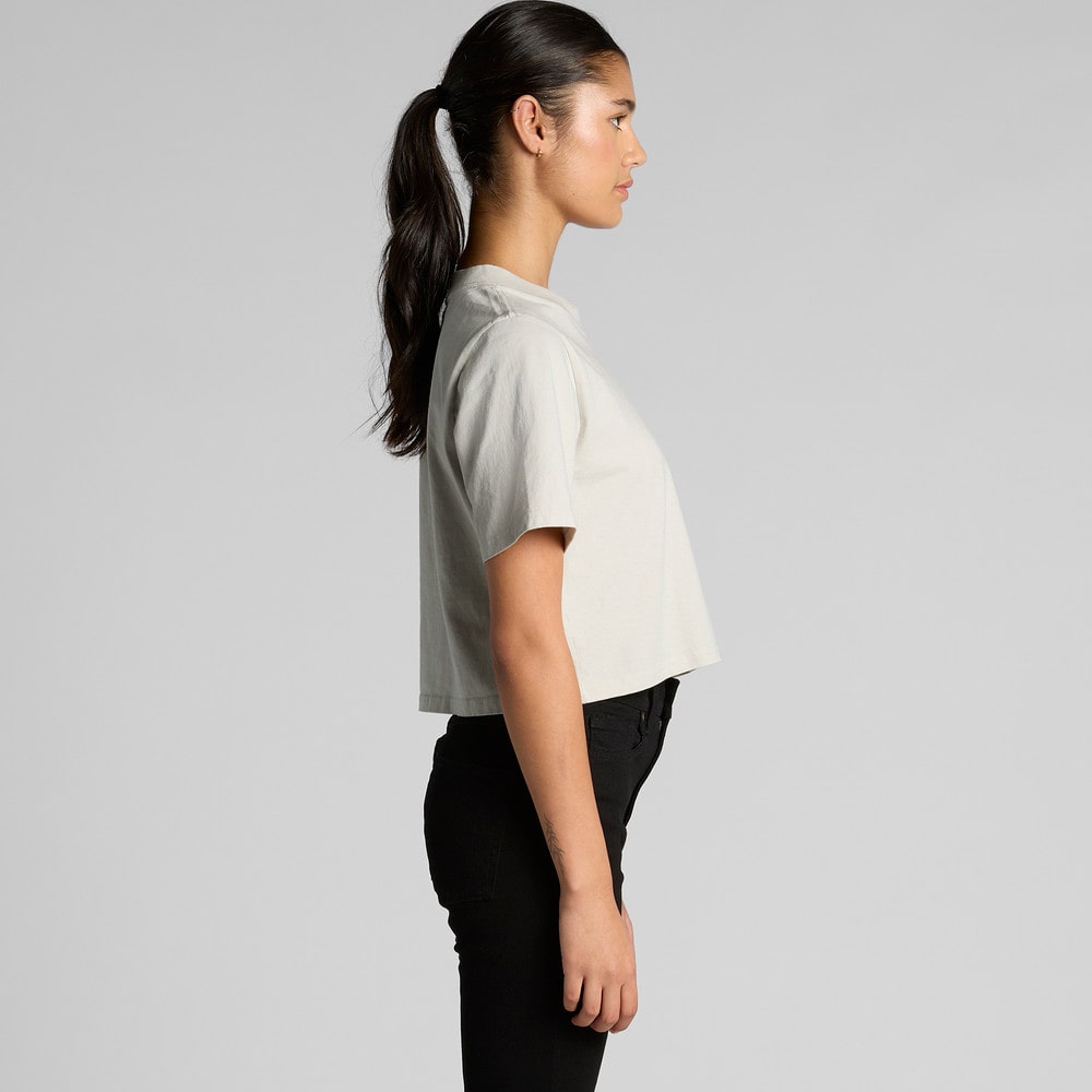 Woman wearing a light gray t-shirt and black pants on a plain background