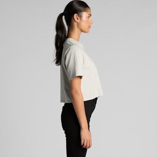 Woman wearing a light gray t-shirt and black pants on a plain background