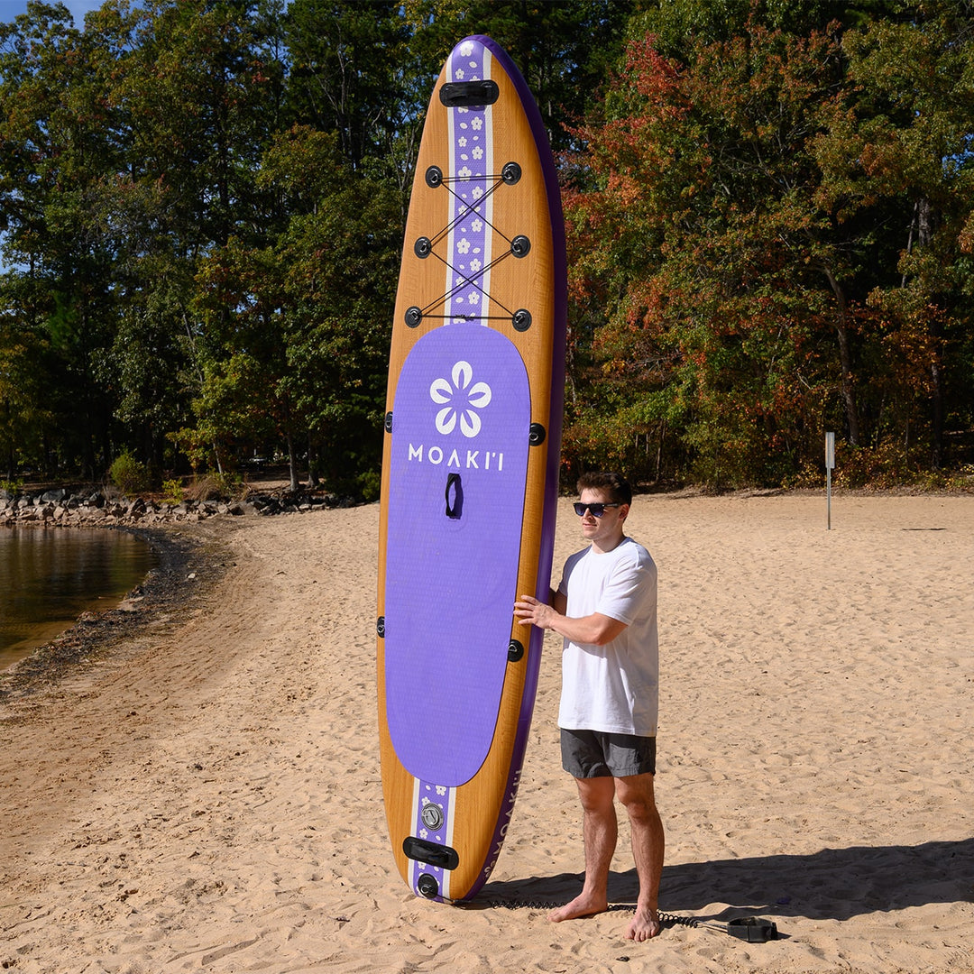 A paddler standing on the beach with the ~19 lb Pathfinder, showcasing its lightweight and portable design.