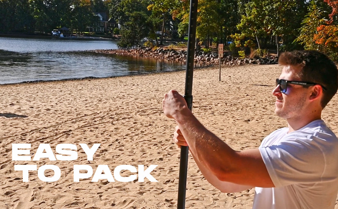 Man holding a SUP paddle on a sandy beach with text 'Easy to Pack' and water and trees in the background.
