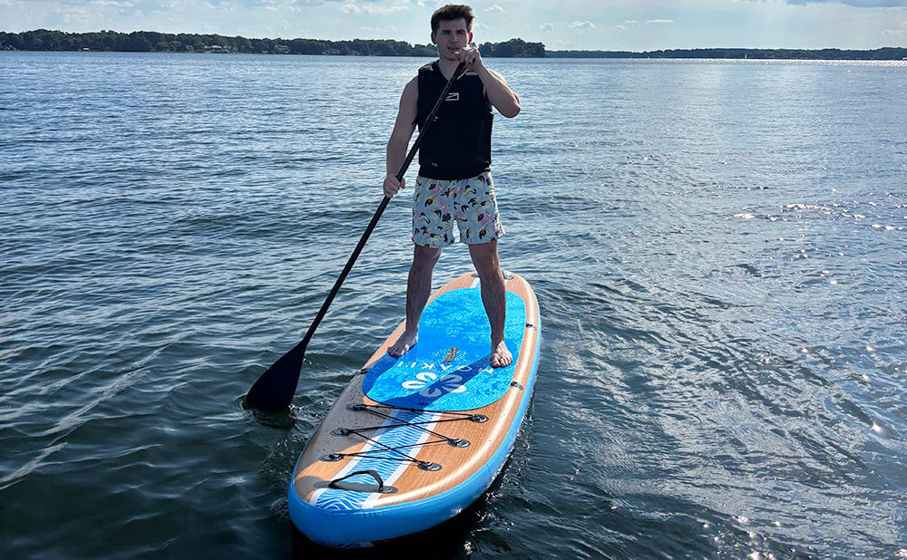 Man paddling the Moaki'i Kiva on calm water, highlighting its straight-line tracking for fitness.