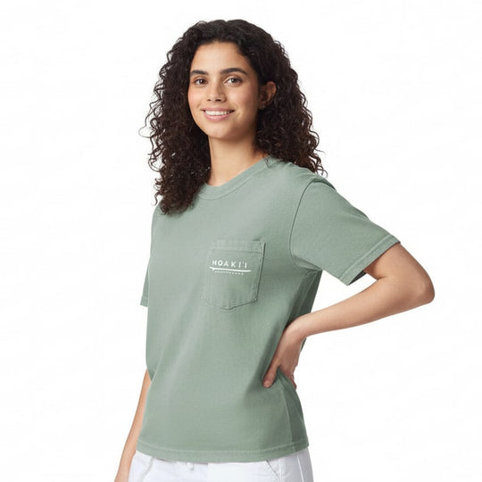 Woman wearing a green t-shirt with a moaki'i logo on a white background