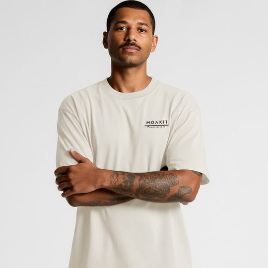 Man wearing a beige t-shirt with a logo on a white background