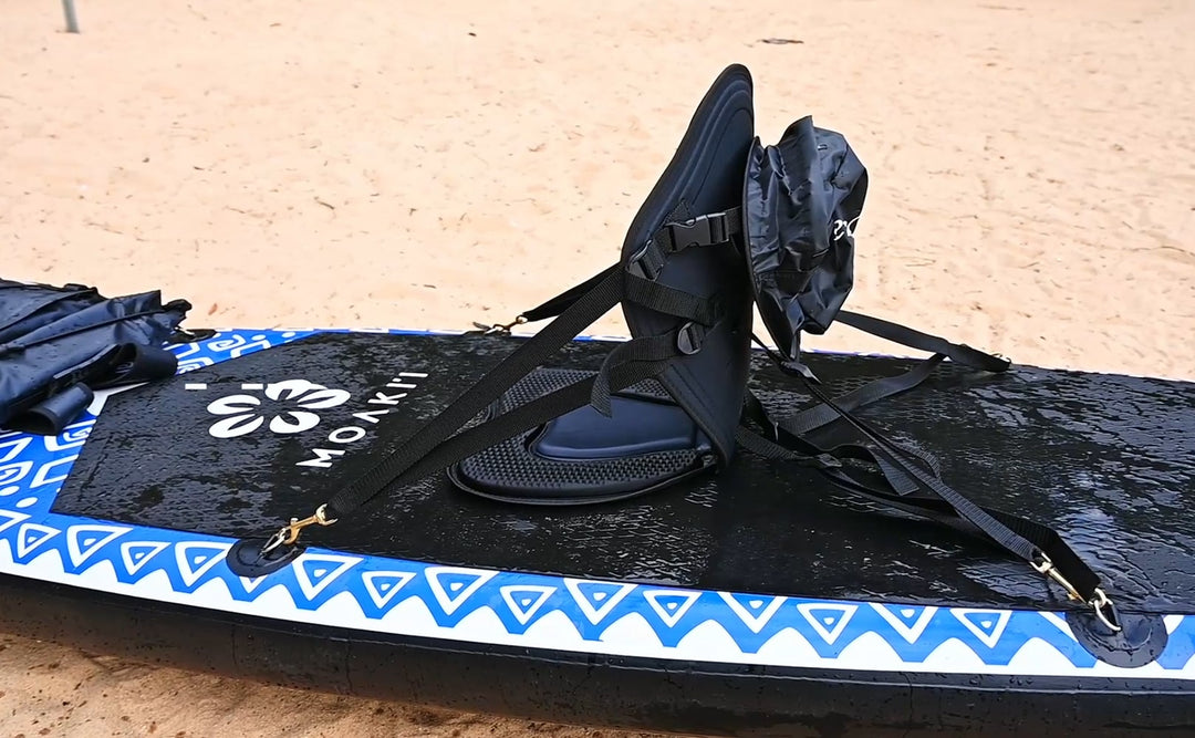 Paddleboard with a seat and straps on a sandy surface