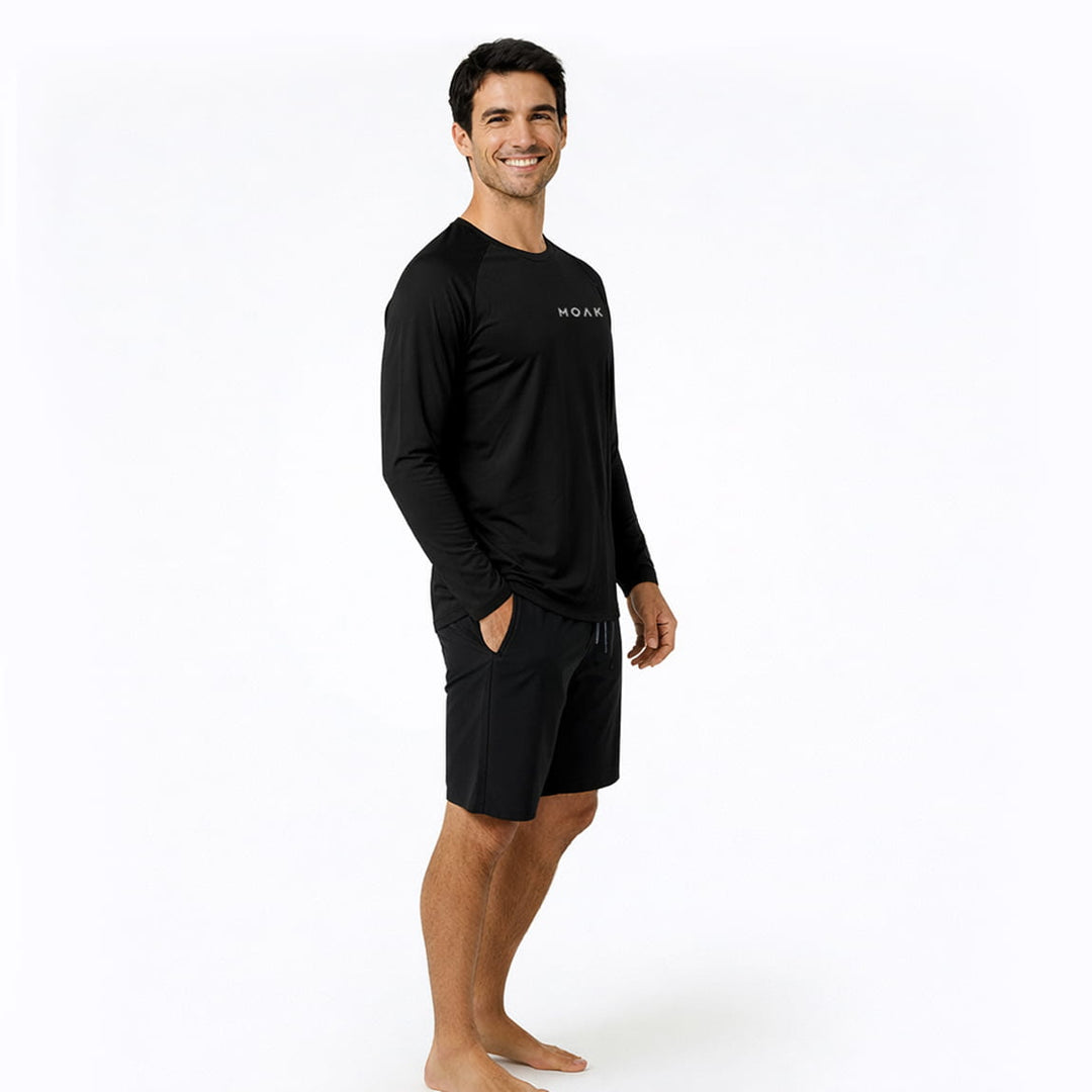 Man wearing a black long-sleeve rash guard and shorts with a Moakii brand logo on a white background