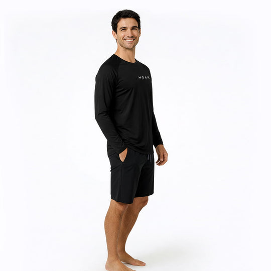Man wearing a black long-sleeve rash guard and shorts with a Moakii brand logo on a white background