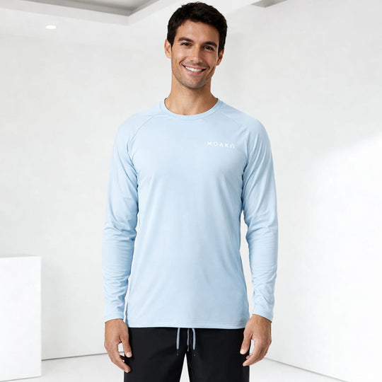 Man wearing a light blue Moaki'i long-sleeve shirt with a brand logo on a white background