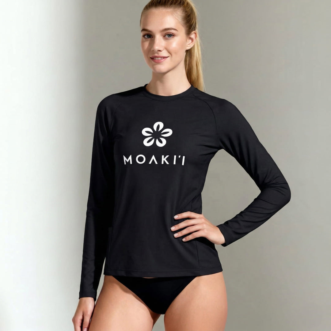 Woman wearing a black long-sleeve watershirt with a logo and text on a plain background
