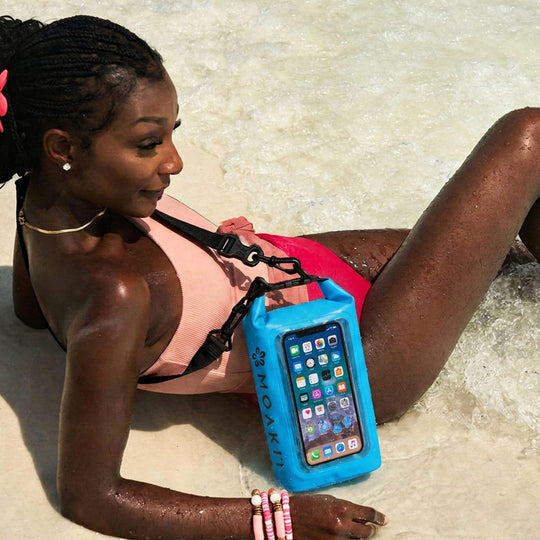 Woman lying on a beach with a blue phone case featuring a smartphone.