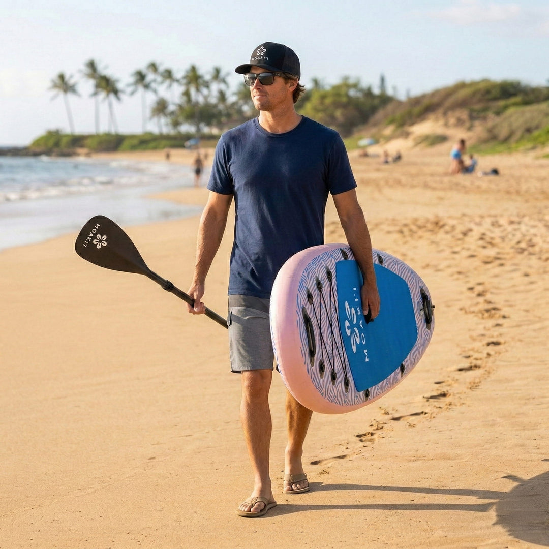 Paddler carrying the Trekker 10'4" on a beach, showing the lightweight and portable design.