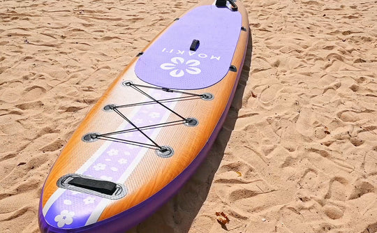 The Moaki'i Pathfinder resting on a beach, showing the beautiful wood-look aesthetic against a natural landscape.