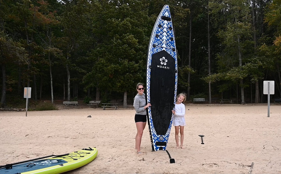 Two paddlers with their Moaki'i boards on the beach, emphasizing the Seeker's 11'6" length.
