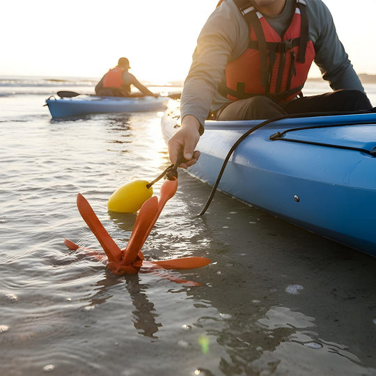 Person in a kayak with a red anchor and yellow buoy on a beach.