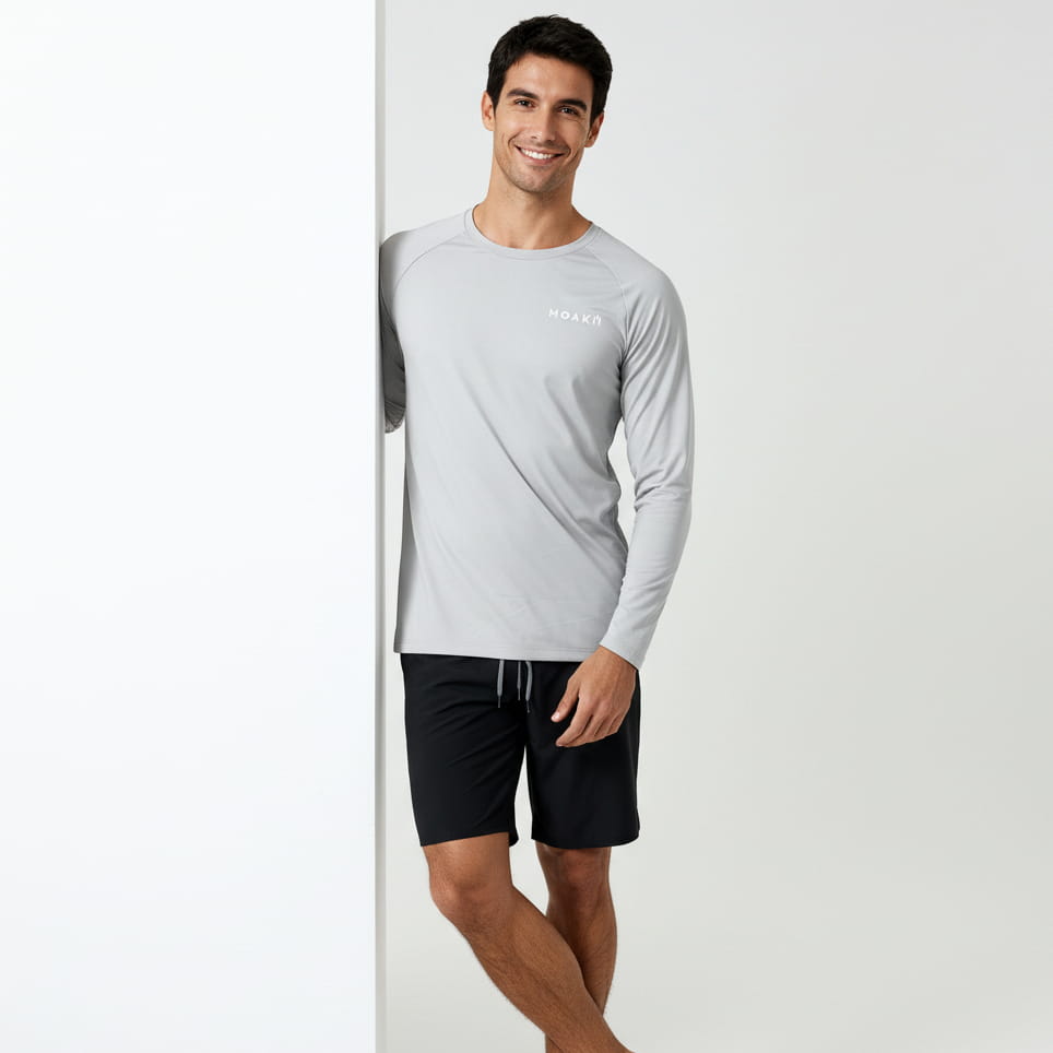 Man wearing a gray long-sleeve rash guard and black shorts on a white background