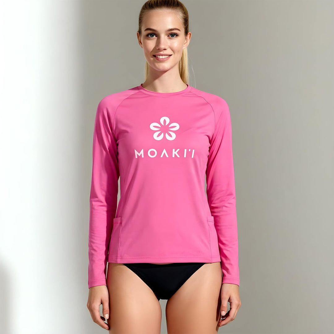 Woman wearing a pink long-sleeve shirt with a logo on a gray background