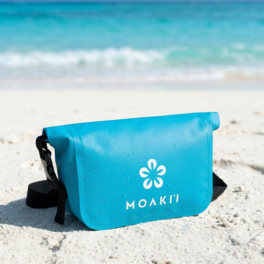 Blue Moaki'i bag on a sandy beach with ocean in the background
