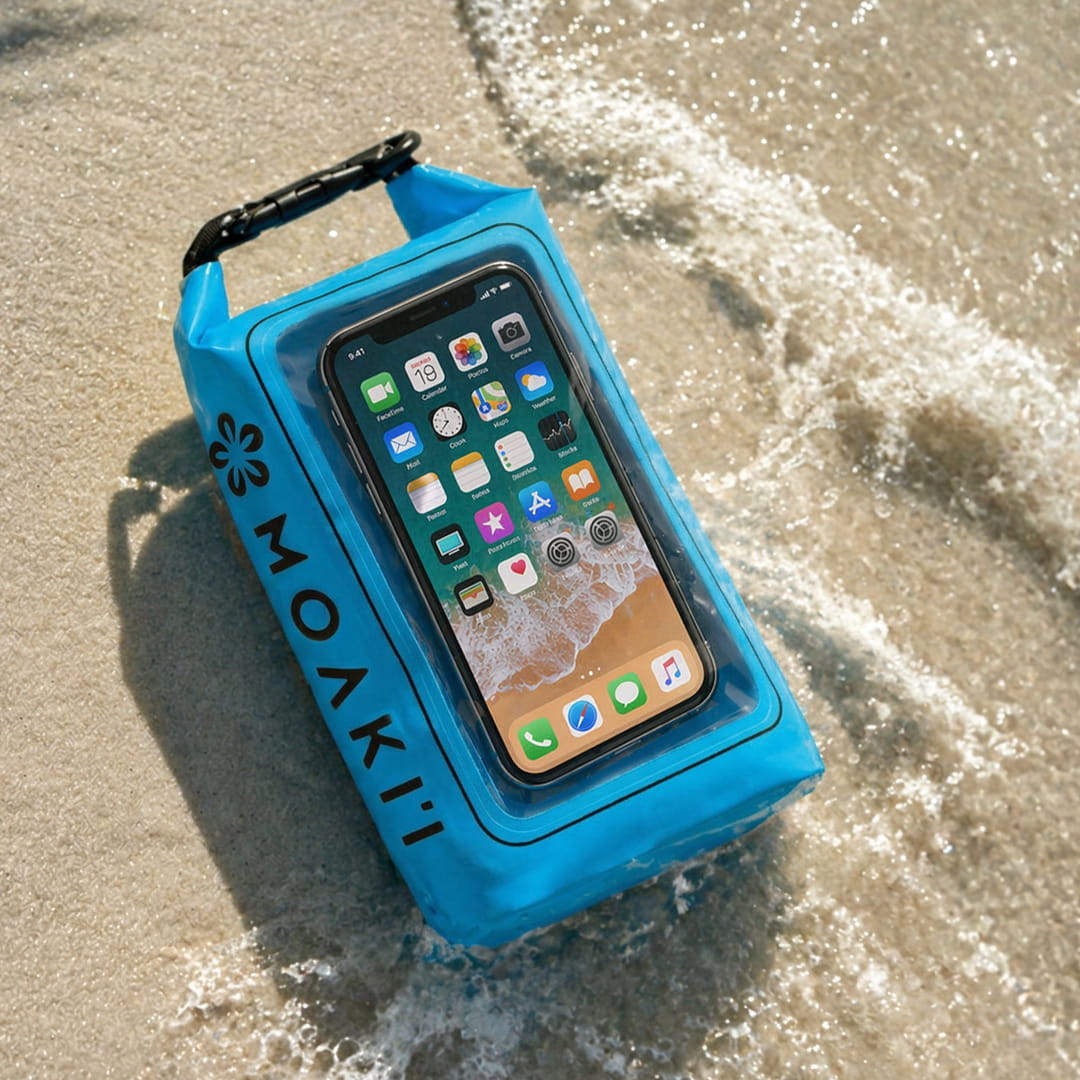 Blue Moakii phone case with a smartphone inside, on sand with water.