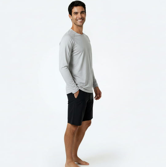 Man wearing a gray long-sleeve shirt and black shorts on a white background