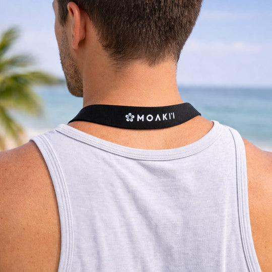Person wearing a black neck strap with 'MOAKII' branding against a beach background