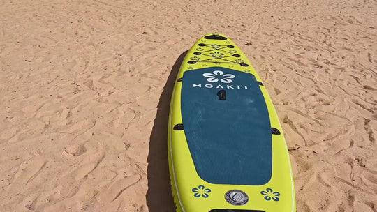 The yellow and blue Moaki'i Trekker resting on a sandy beach.