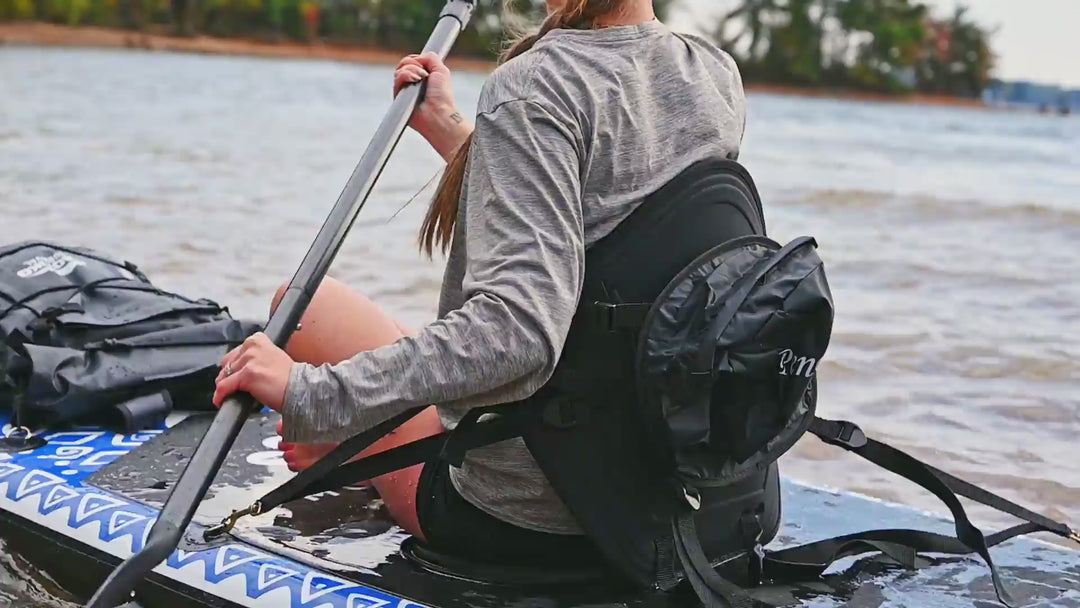 A video of a woman sitting on a paddleboard on a lake and holding a paddle