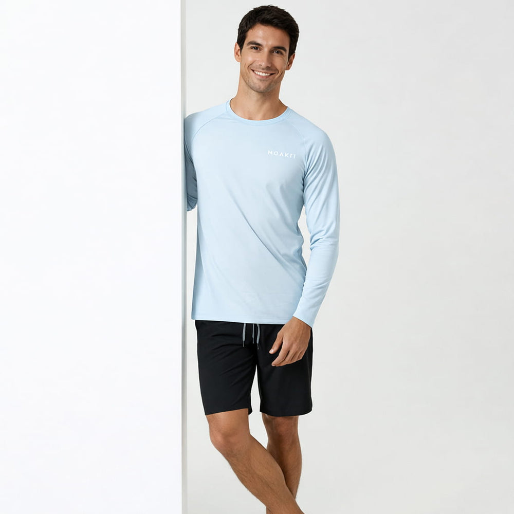 Man wearing a light blue long-sleeve athletic shirt and black shorts on a white background