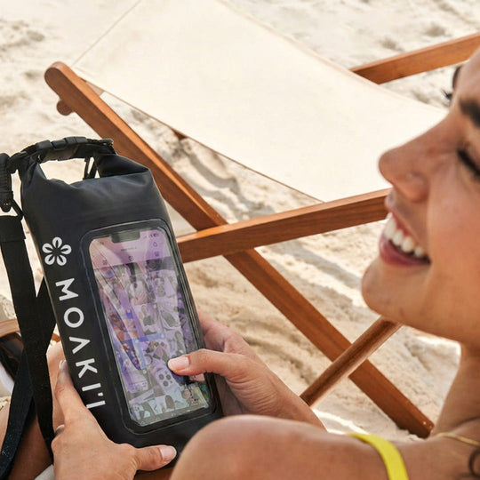 Person using a phone with a Moakii case on a beach