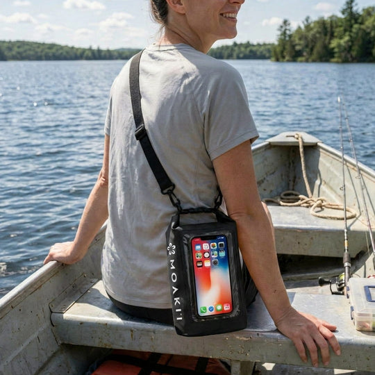 Person sitting in a boat with a Moakii phone case displaying an iPhone.