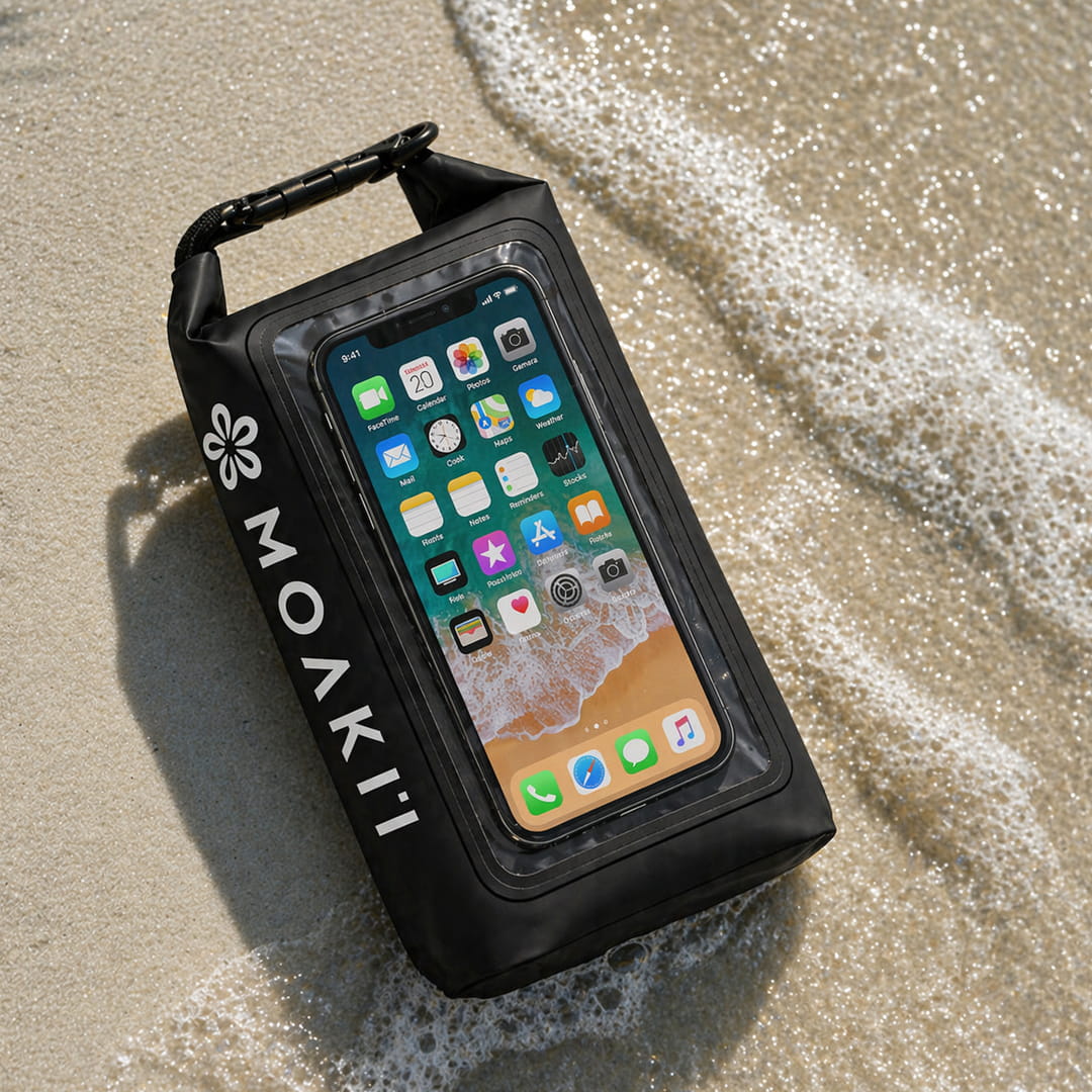 Black waterproof phone case with smartphone displaying app icons on a sandy beach.